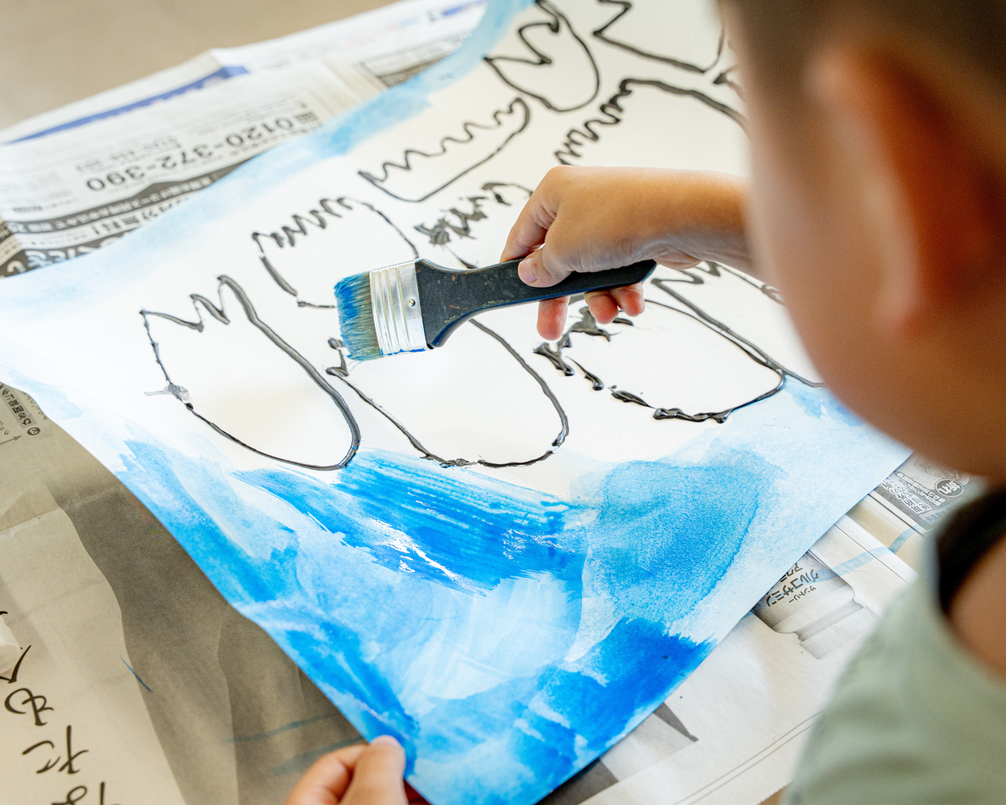 大きな筆で青い絵を描く手元